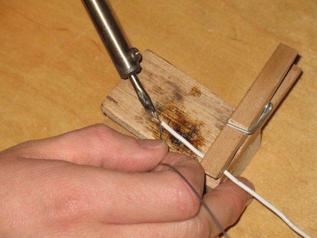 Photobeschreibung: Auf dem Photo ist die Löthilfe mit eingespanntem Kabel, dem Lötzinn, und einem Lötkolben zu sehen.